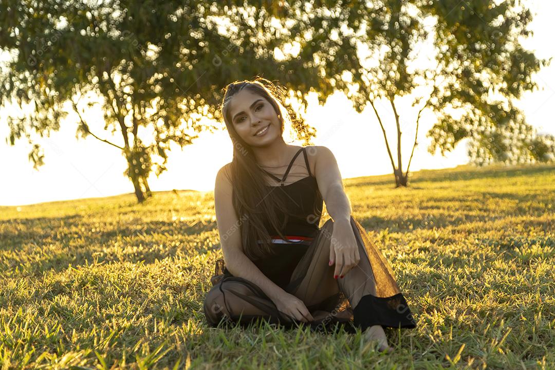 Linda menina morena posando em fotos na natureza por do sol