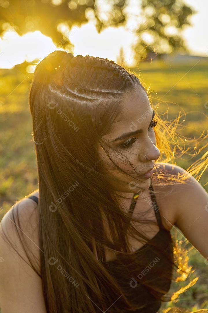 Linda menina morena posando em fotos na natureza por do sol