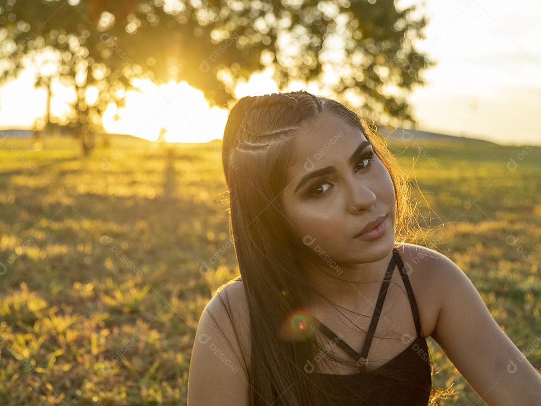 Linda menina morena posando em fotos na natureza por do sol