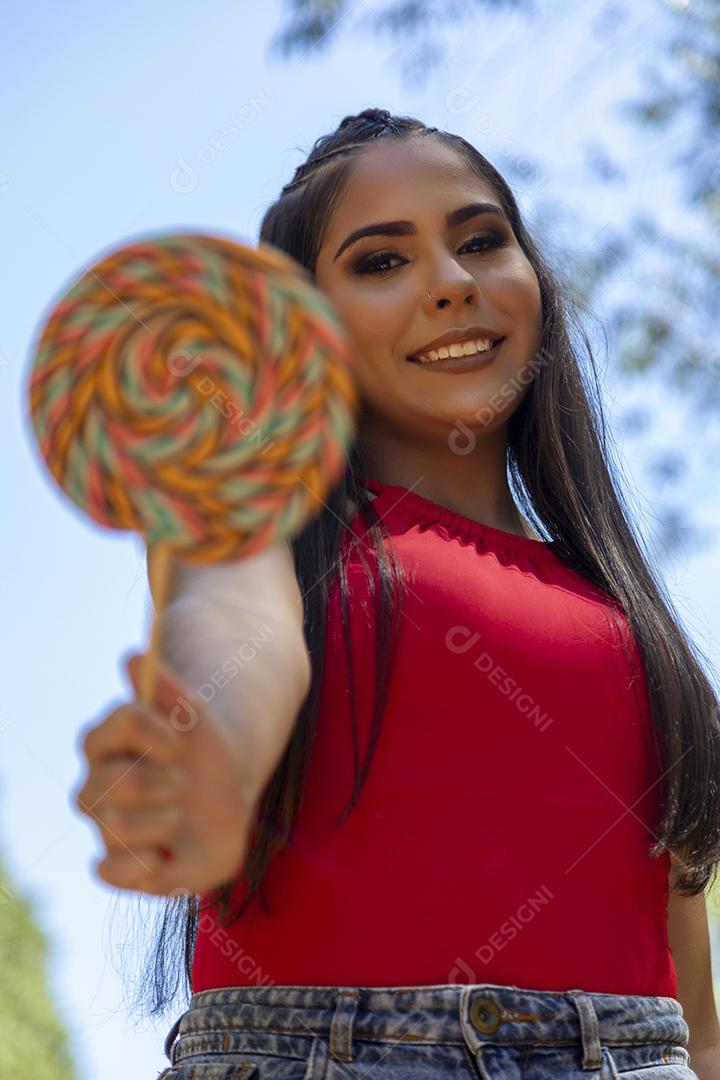 Beautiful brunette girl holding colorful lollipop in the forest
