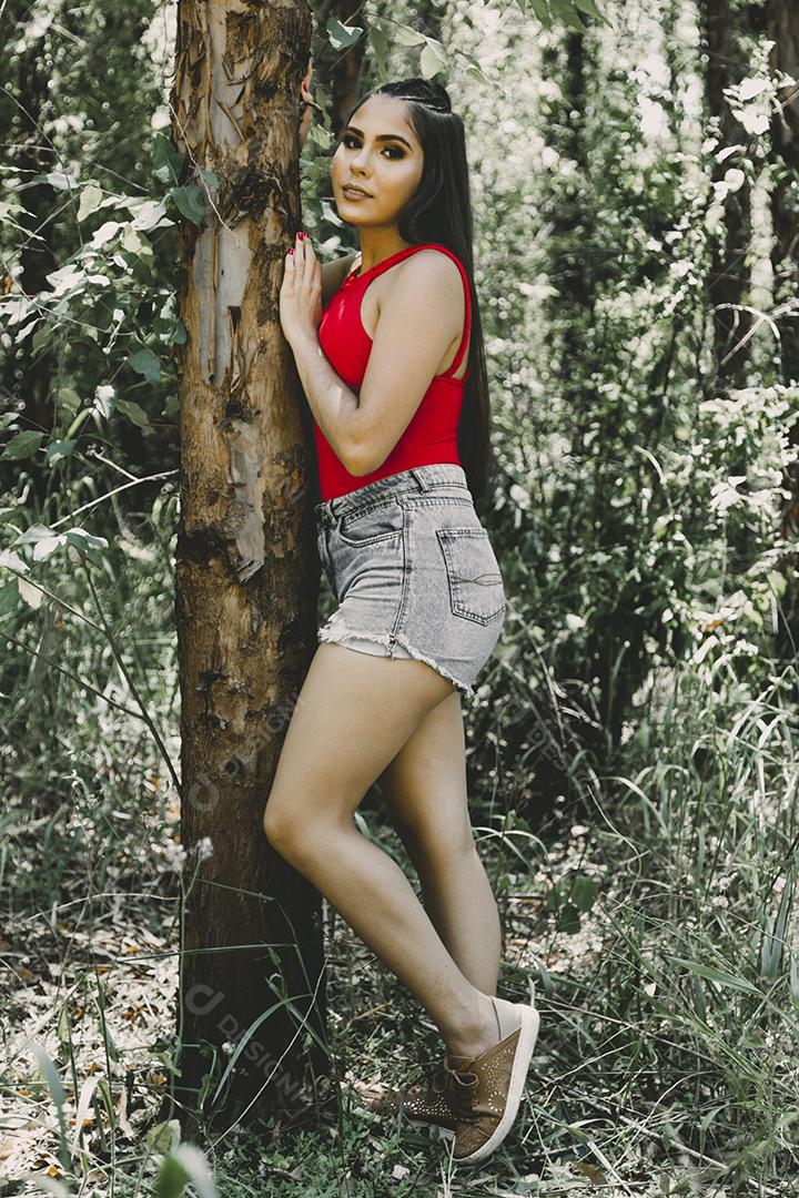 Linda menina morena segurando pirulito colorido na floresta