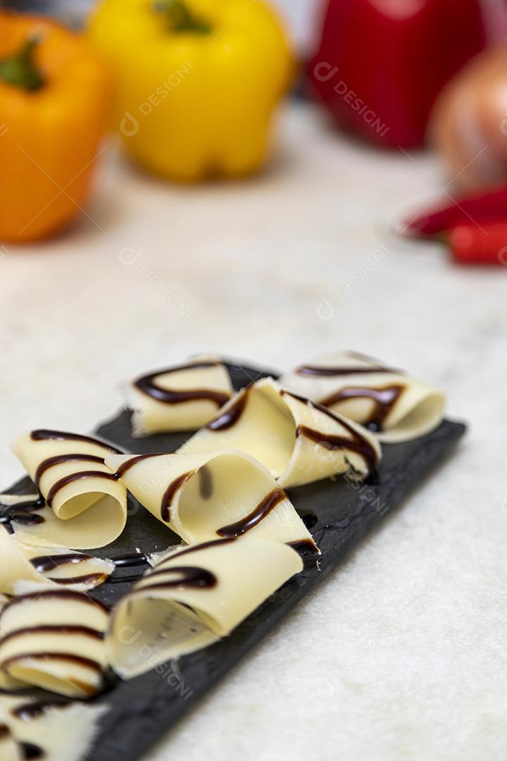 Porção de queijo parmesão em flocos com vinagre balsâmico em pedra preta