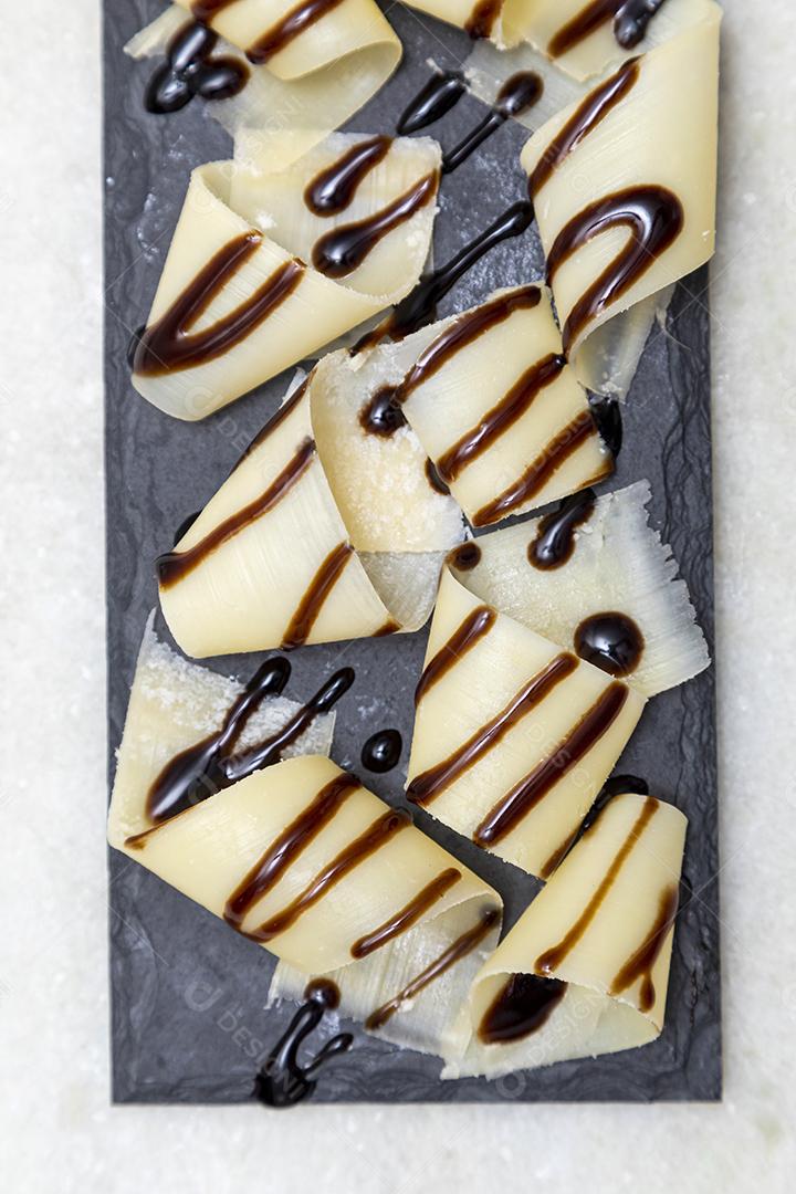 Porção de queijo parmesão em flocos com vinagre balsâmico em pedra preta