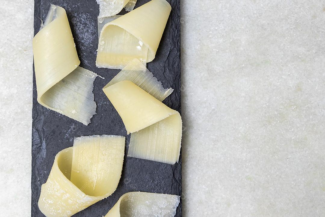 Porção de queijo parmesão em flocos com vinagre balsâmico em pedra preta