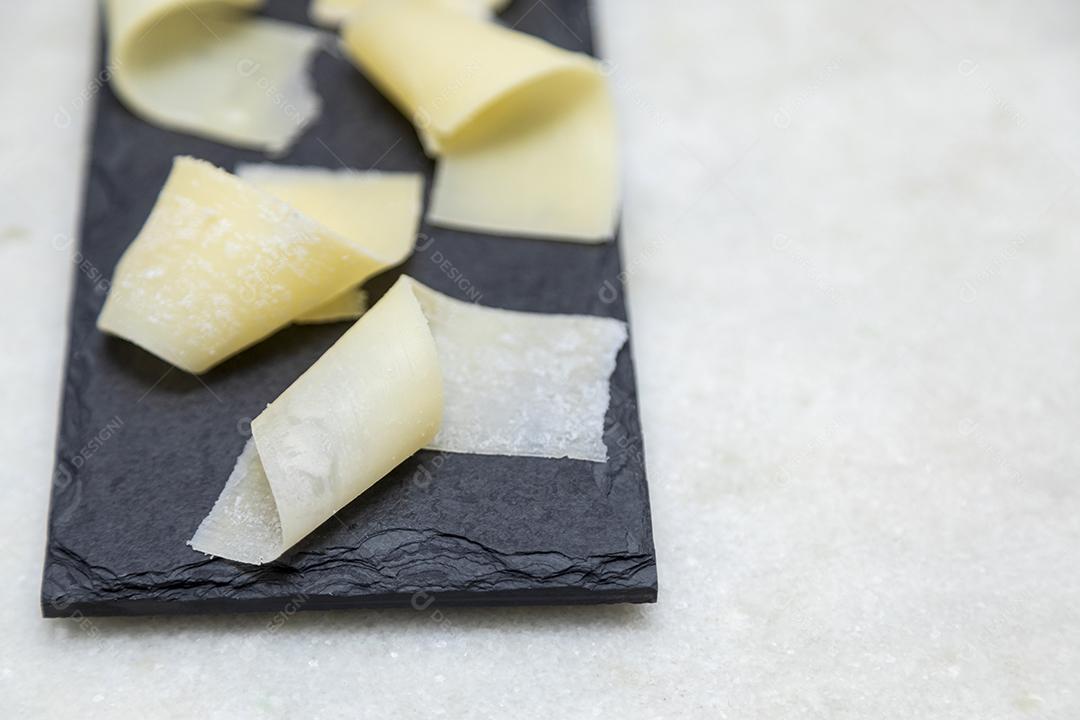 Porção de queijo parmesão em flocos com vinagre balsâmico em pedra preta