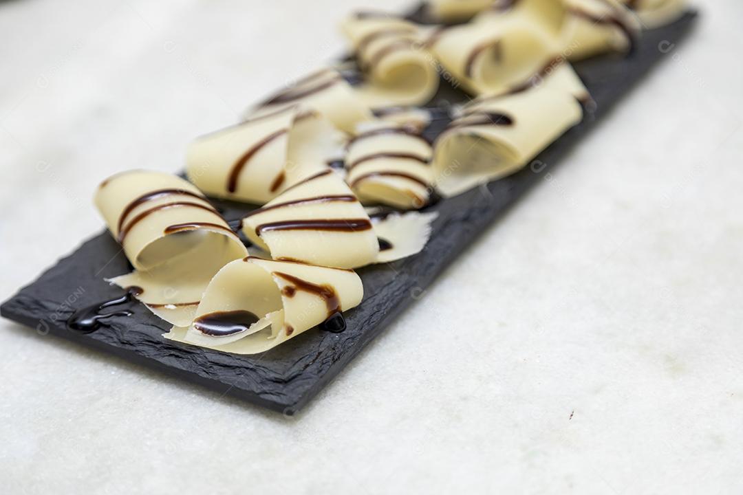 Porção de queijo parmesão em flocos com vinagre balsâmico em pedra preta