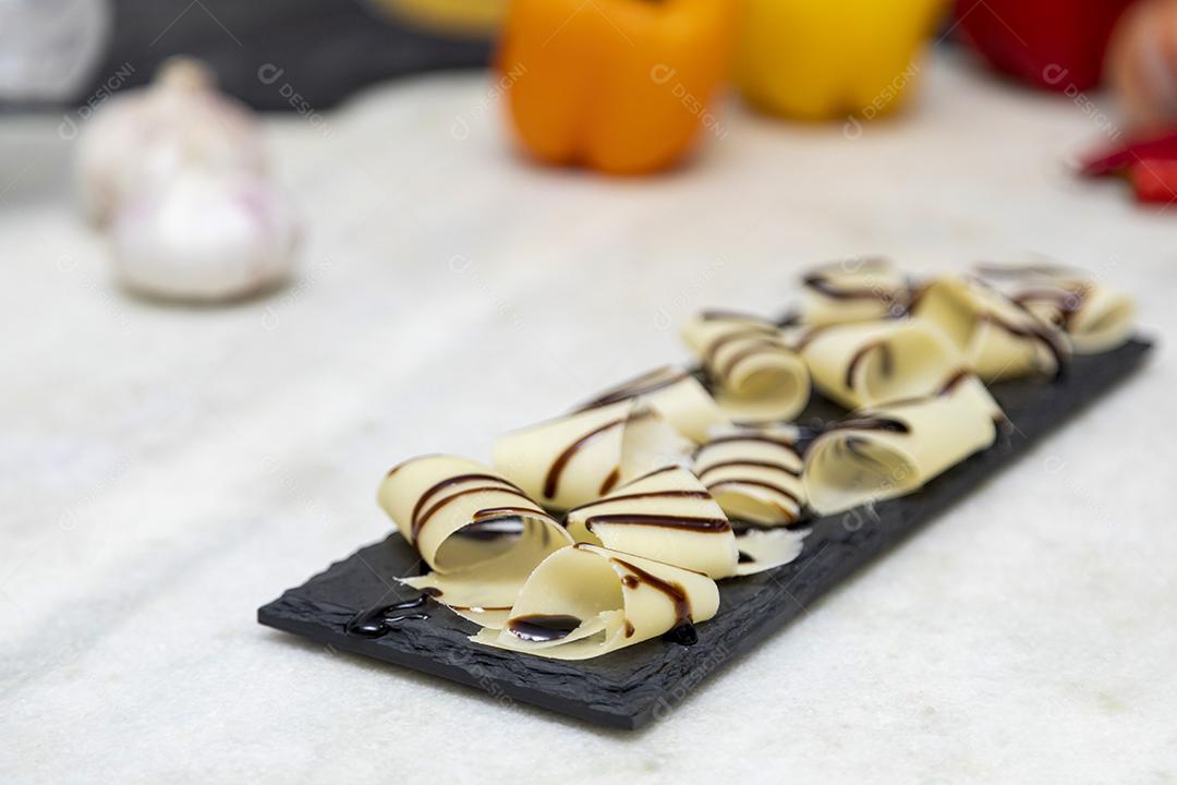 Porção de queijo parmesão em flocos com vinagre balsâmico em pedra preta