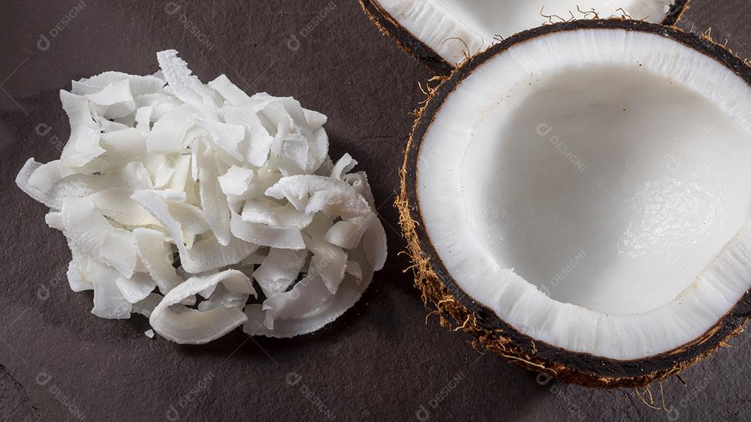 Coco aberto no meio em cima da pedra com lascas de coco Imagem JPG