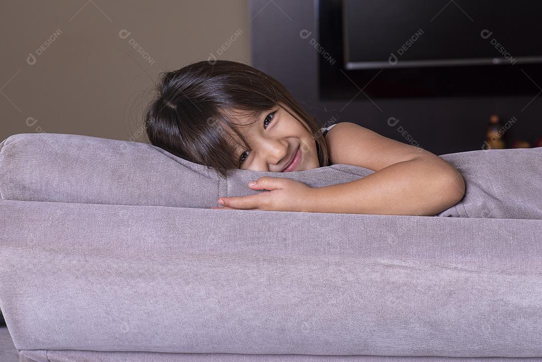 Menina bonita feliz brincando no sofá JPG