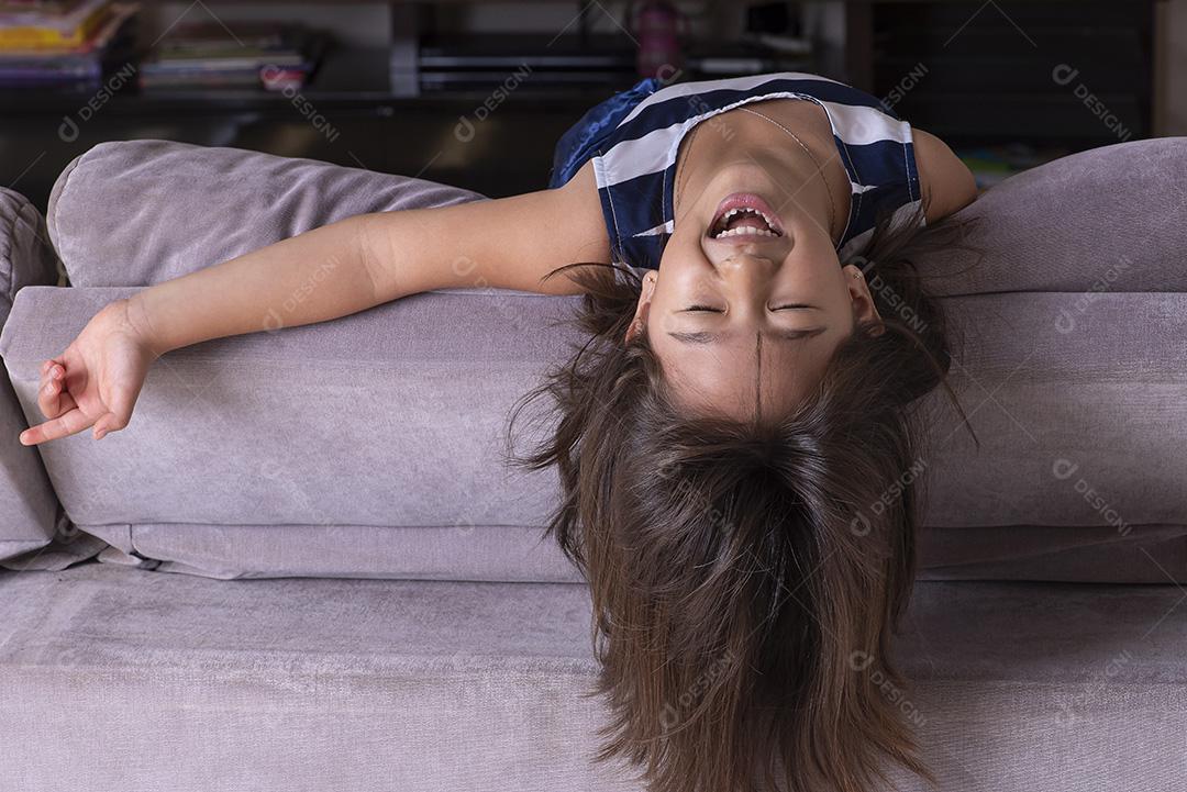 Menina bonita feliz brincando no sofá JPG
