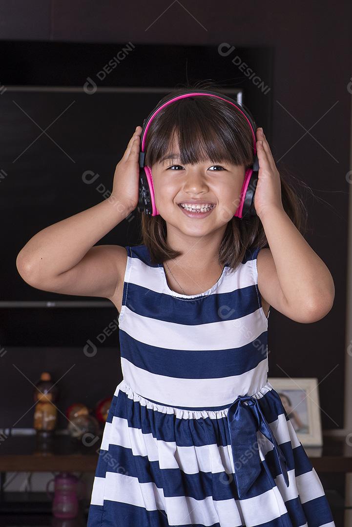 Menina bonitinha feliz ouvindo música no sofá em casa JPG