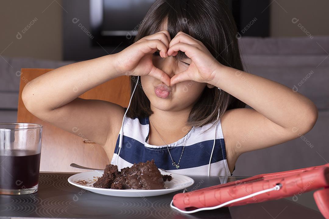 Menina bonita feliz assistindo tablet e comendo chocolate JPG