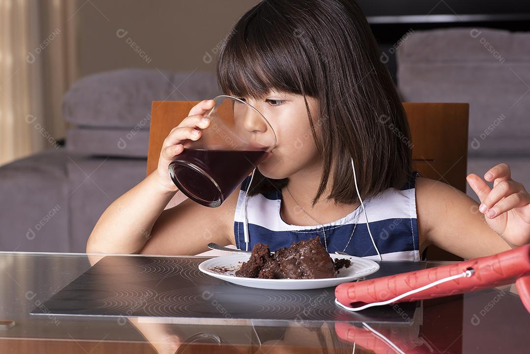 Menina bonita feliz assistindo tablet e comendo chocolate JPG