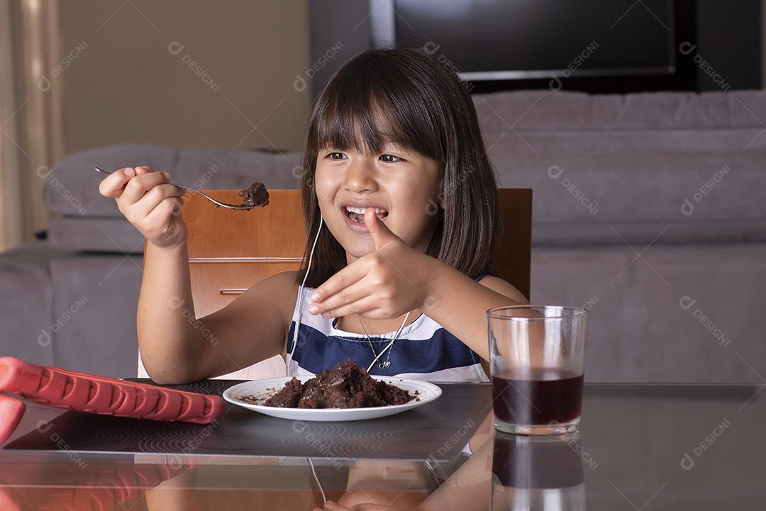 Menina bonita feliz assistindo tablet e comendo chocolate JPG