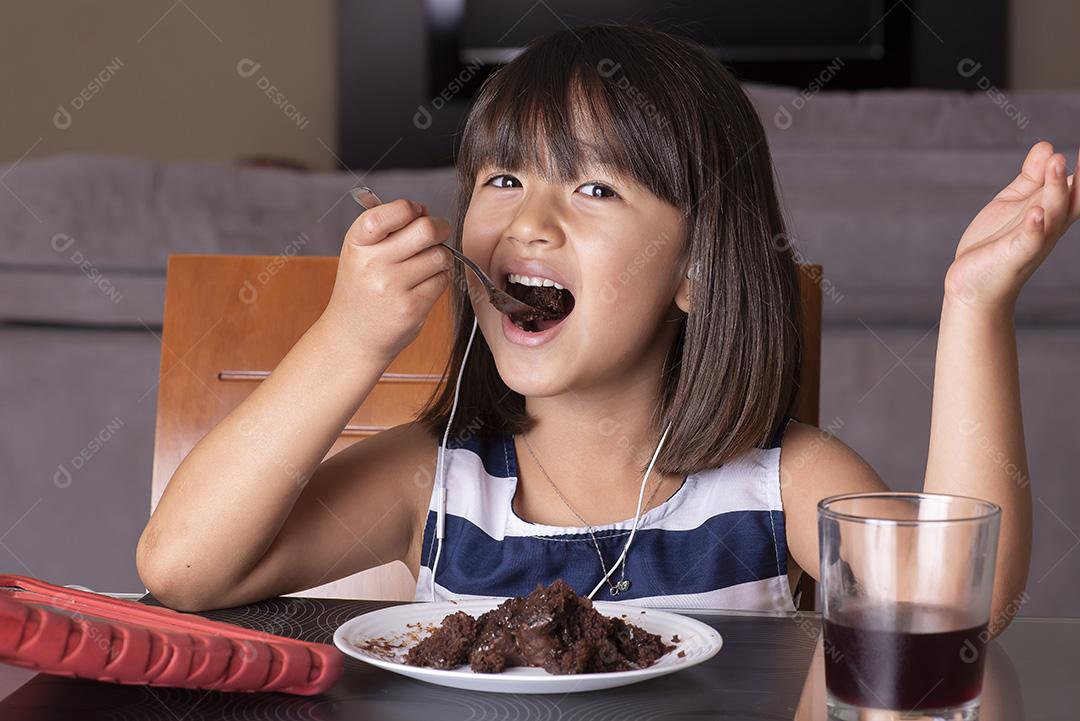 Menina bonita feliz assistindo tablet e comendo chocolate JPG