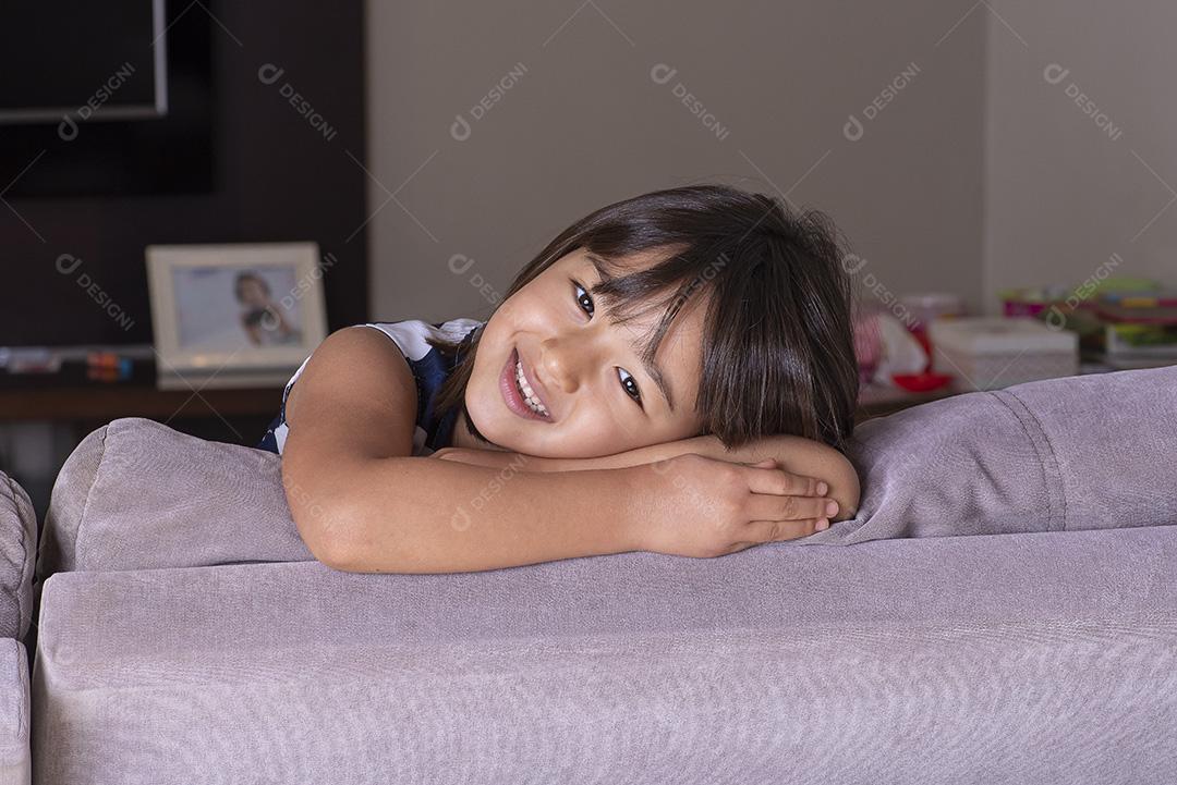 Feliz menina bonita brincando no sofá JPG