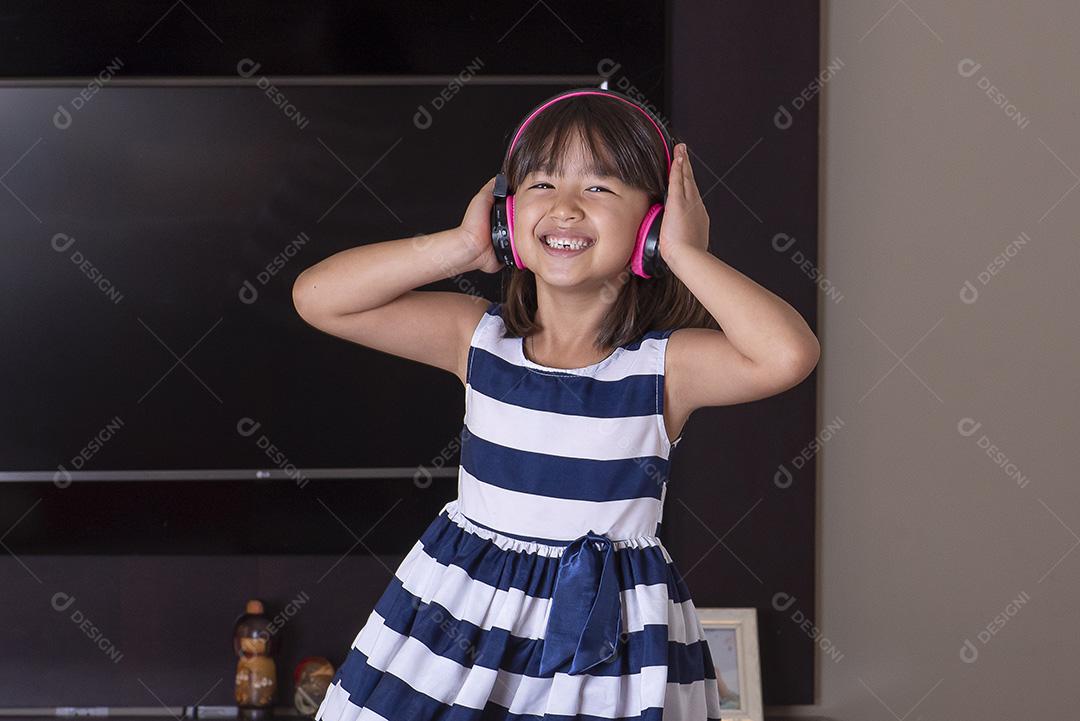 Menina bonitinha feliz ouvindo música no sofá em casa JPG