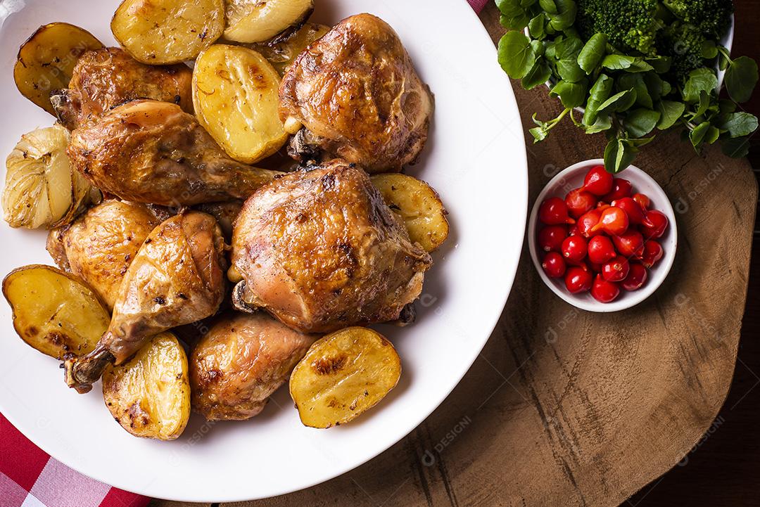 Frango assado em pedaços com batatas e cebola em um prato branco JPG