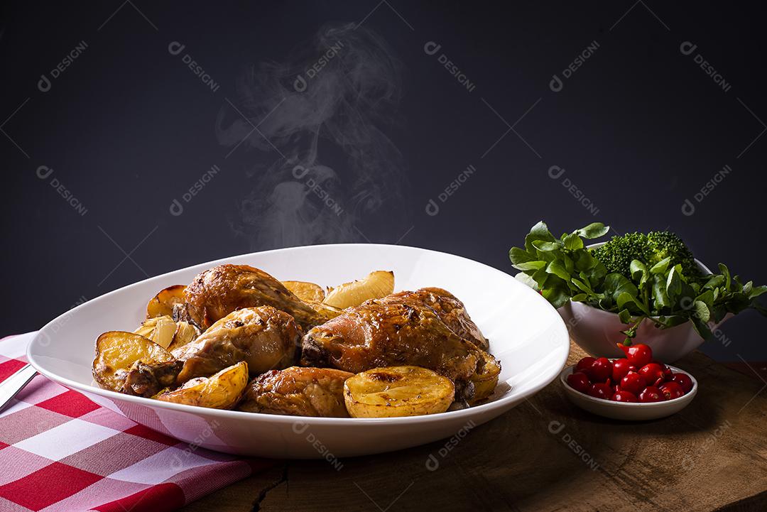 Frango assado em pedaços com batatas e cebola em um prato branco JPG