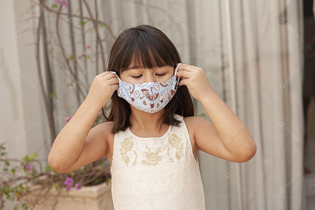 Garota asiática usando uma máscara para se proteger de Covid JPG