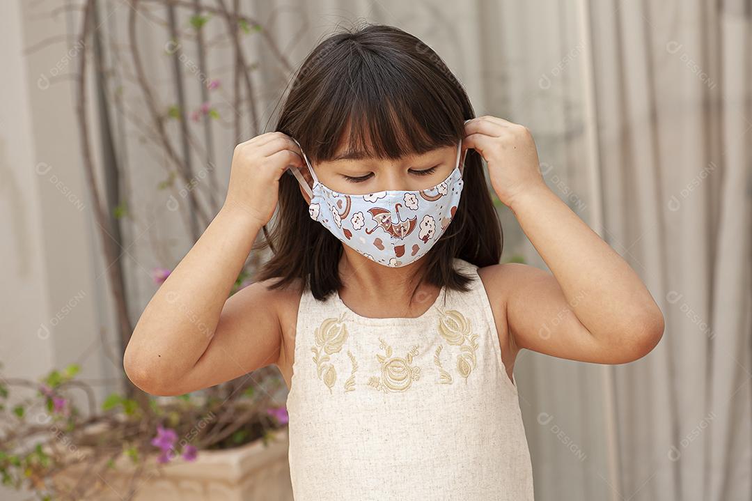Garota asiática usando uma máscara para se proteger de Covid JPG