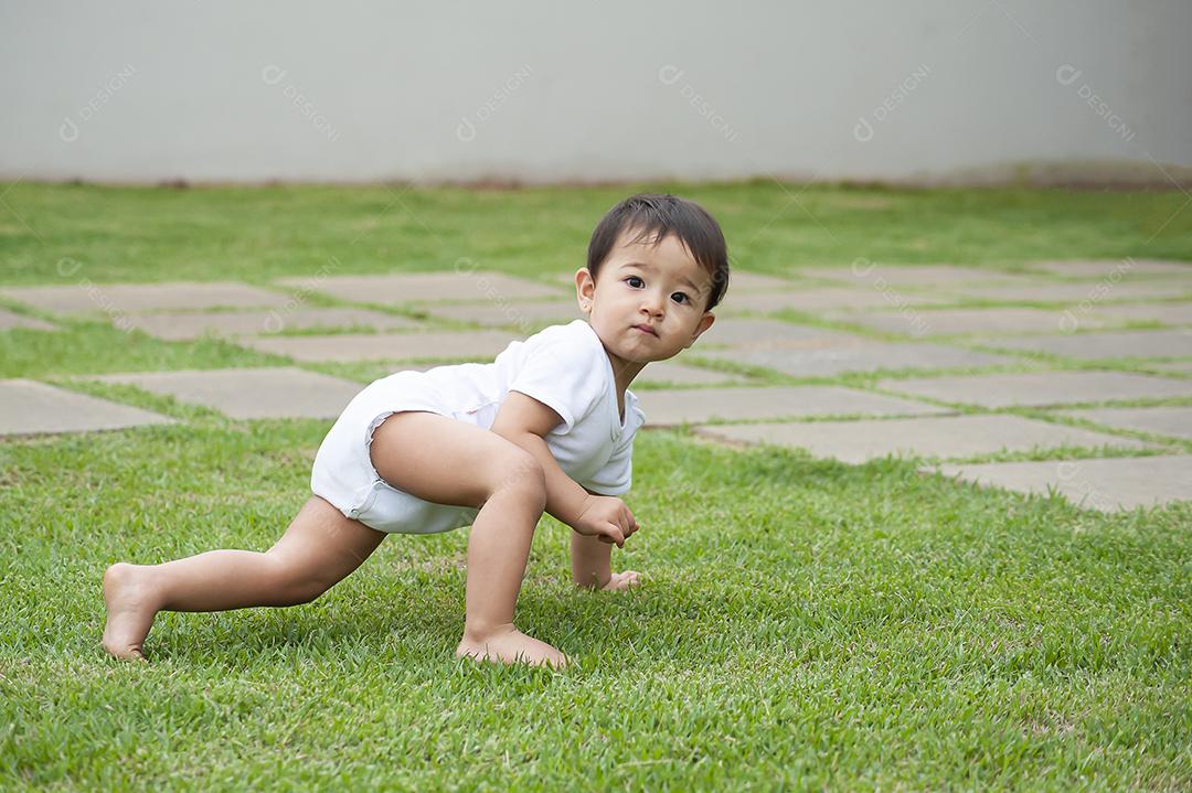 Garota de 1 ano de aparência asiática brincando na grama da fazenda JPG