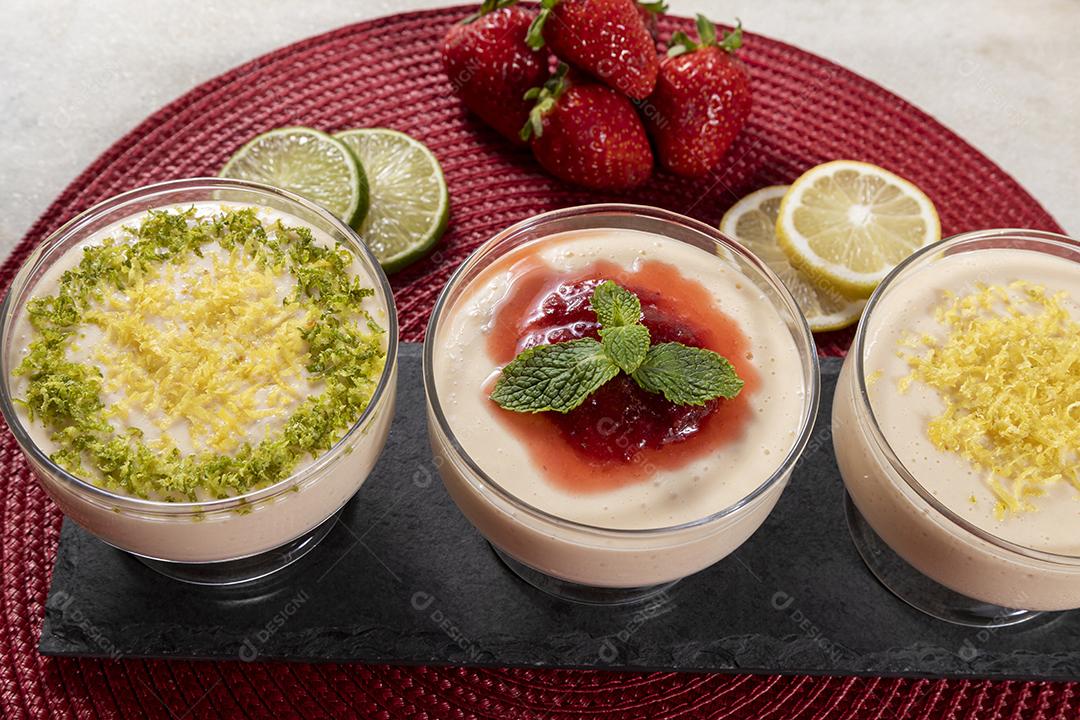 Deliciosos mousses de limão e morango em frascos de vidro em cima Imagem JPG
