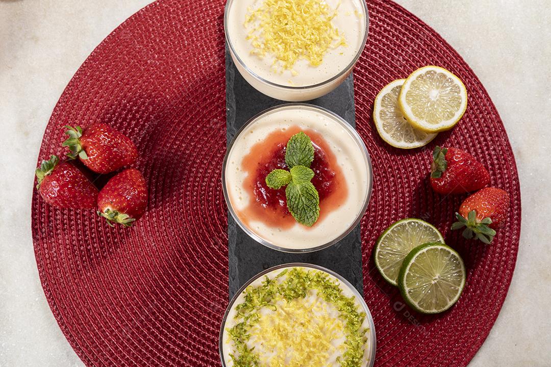 Deliciosos mousses de limão e morango em frascos de vidro em cima Imagem JPG