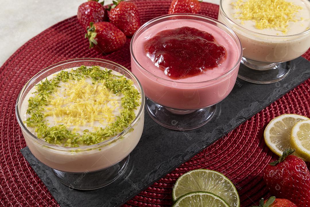 Deliciosos mousses de limão e morango em frascos de vidro em cima Imagem JPG