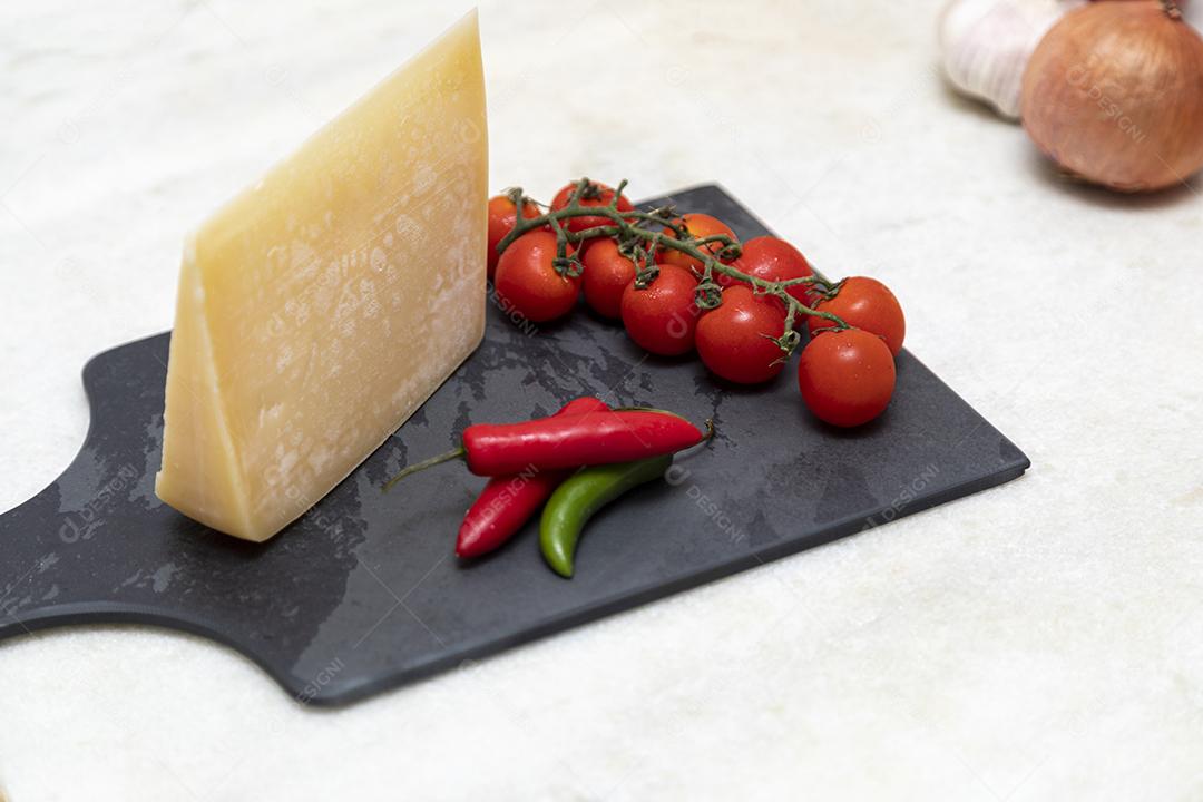 Queijo parmesão no tabuleiro de pedra preta com especiarias