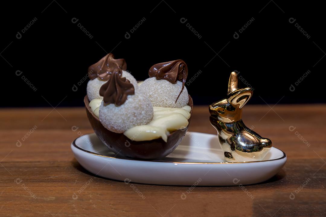Ovos de Páscoa de chocolate em tigela com coelho de porcelana Imagem JPG