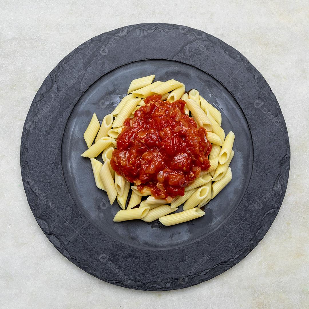 Massa penne com molho vermelho e queijo parmesão em um prato preto