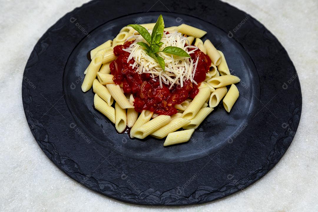 Penne pasta with red sauce and Parmesan cheese on a black plate