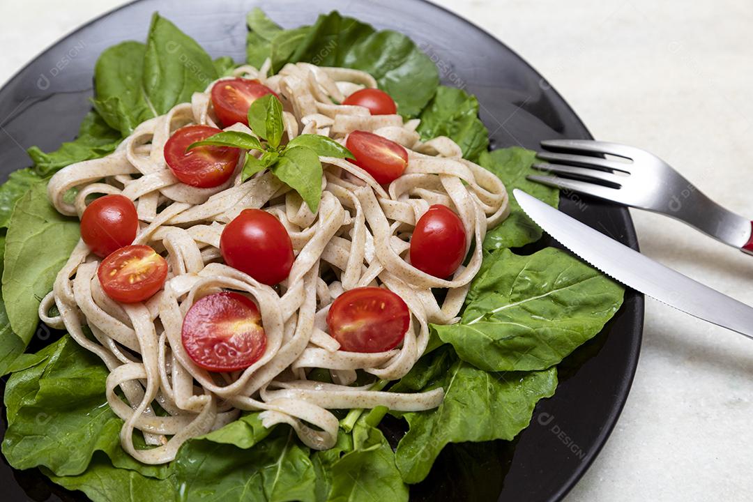 Massa integral com folhas verdes de rúcula e tomate cereja