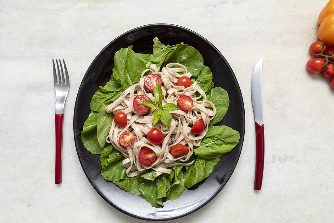 Massa integral com folhas verdes de rúcula e tomate cereja