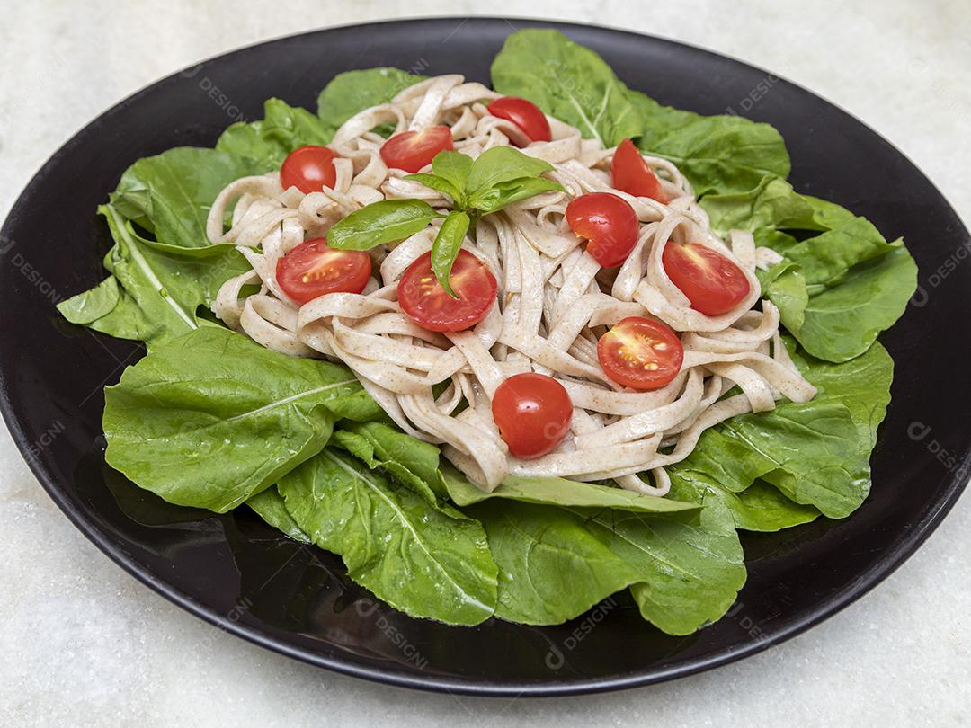 Massa integral com folhas verdes de rúcula e tomate cereja