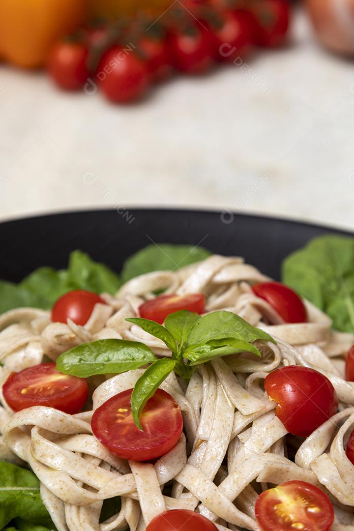 Massa integral com folhas verdes de rúcula e tomate cereja