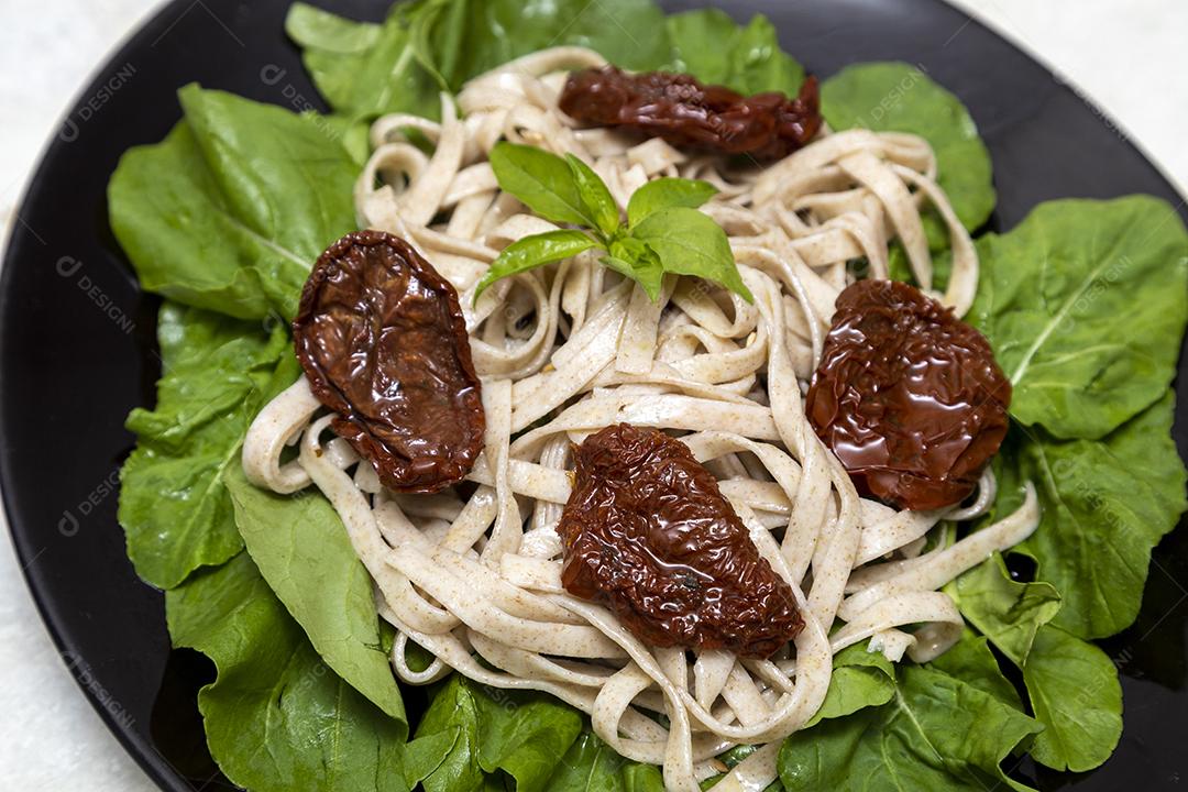 massa integral com folhas verdes de rúcula e tomate seco