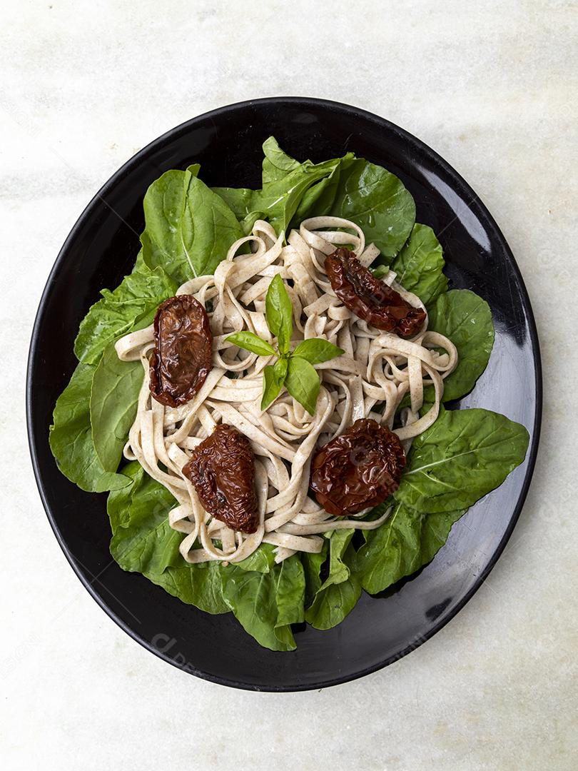 massa integral com folhas verdes de rúcula e tomate seco