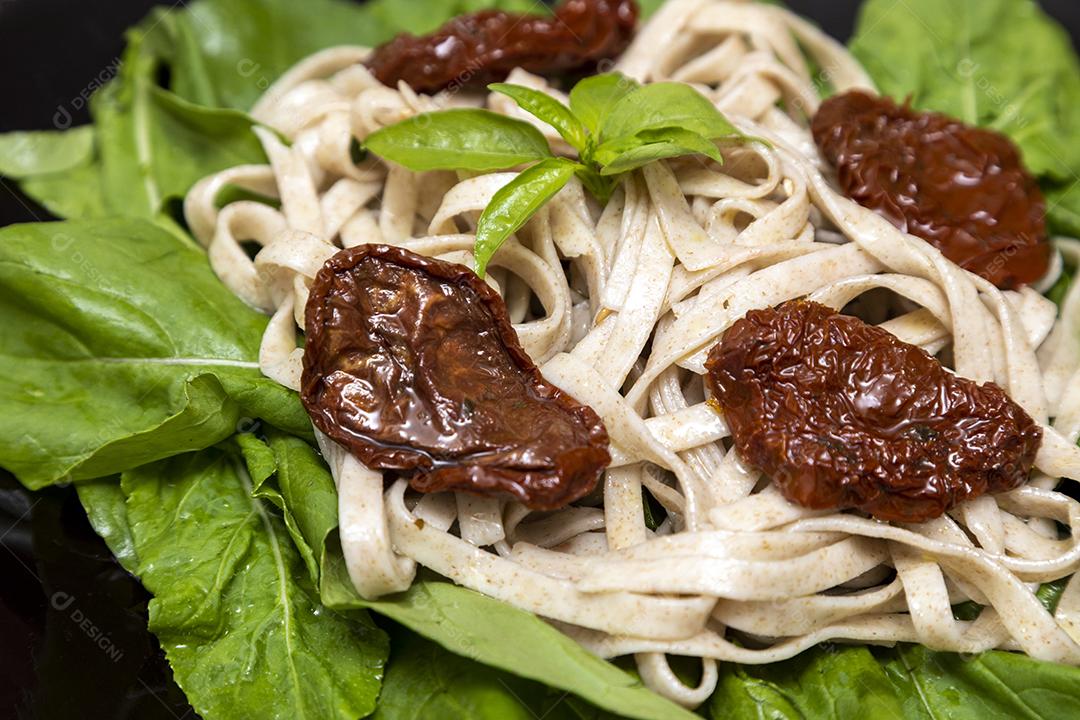 massa integral com folhas verdes de rúcula e tomate seco