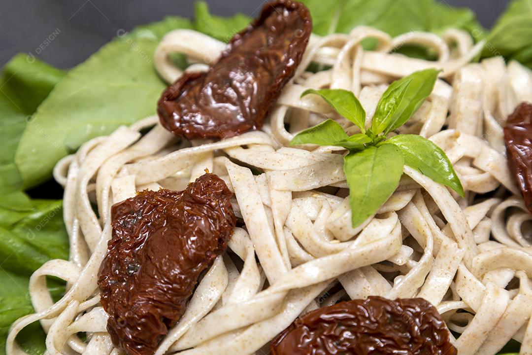 massa integral com folhas verdes de rúcula e tomate seco