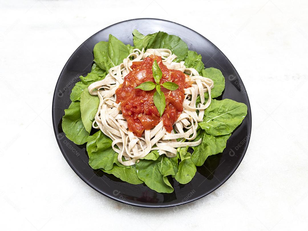 massa de massa integral com folhas verdes de rúcula, molho vermelho