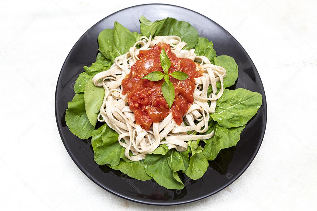 massa de massa integral com folhas verdes de rúcula, molho vermelho