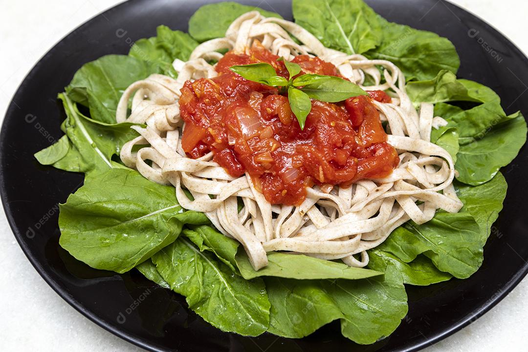 massa de massa integral com folhas verdes de rúcula, molho vermelho