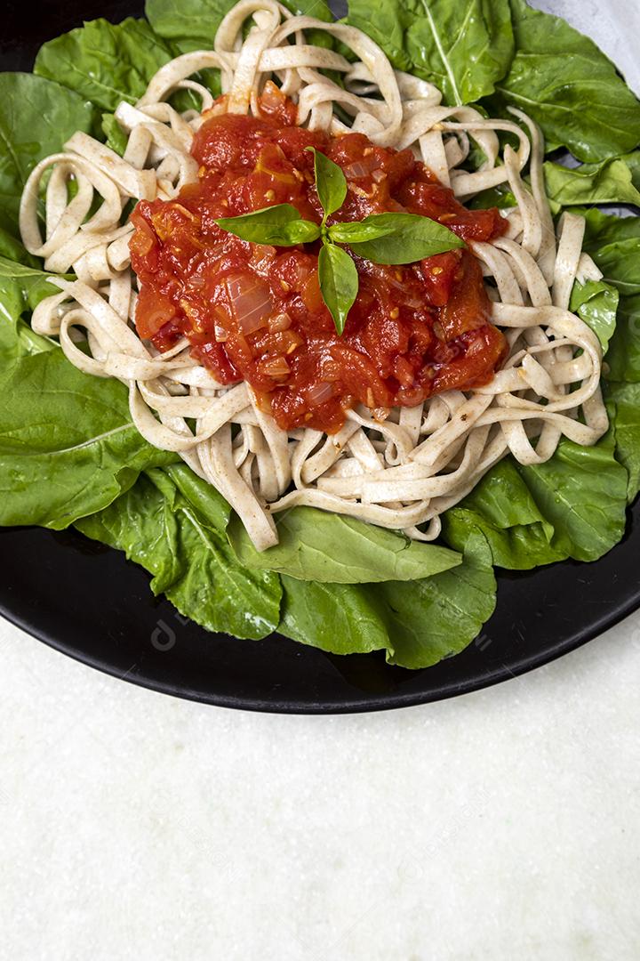 massa de massa integral com folhas verdes de rúcula, molho vermelho