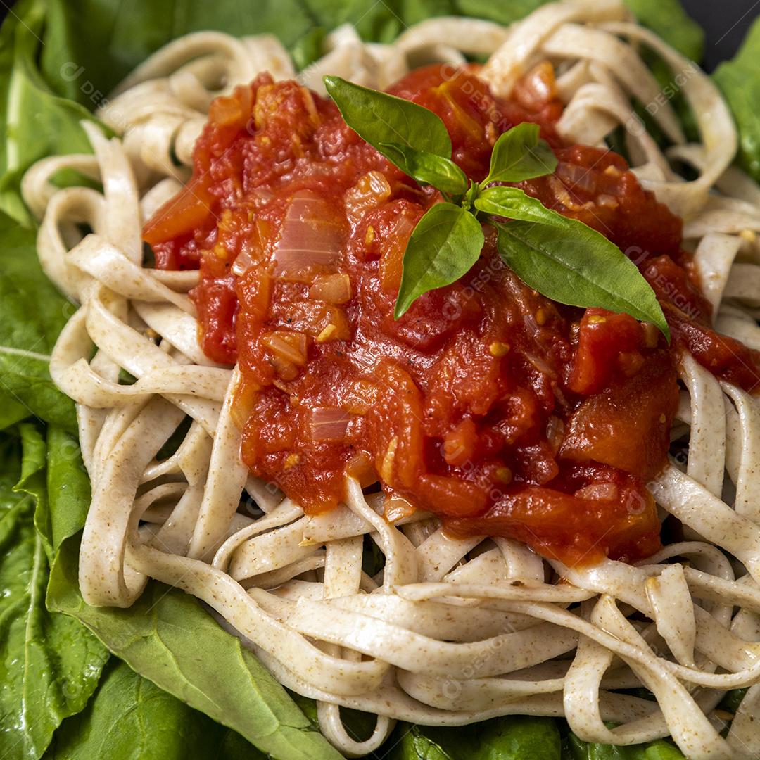 massa de massa integral com folhas verdes de rúcula, molho vermelho