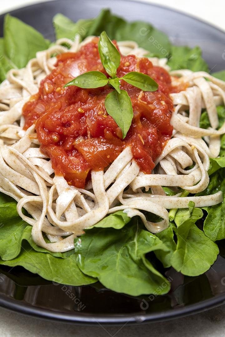 massa de massa integral com folhas verdes de rúcula, molho vermelho