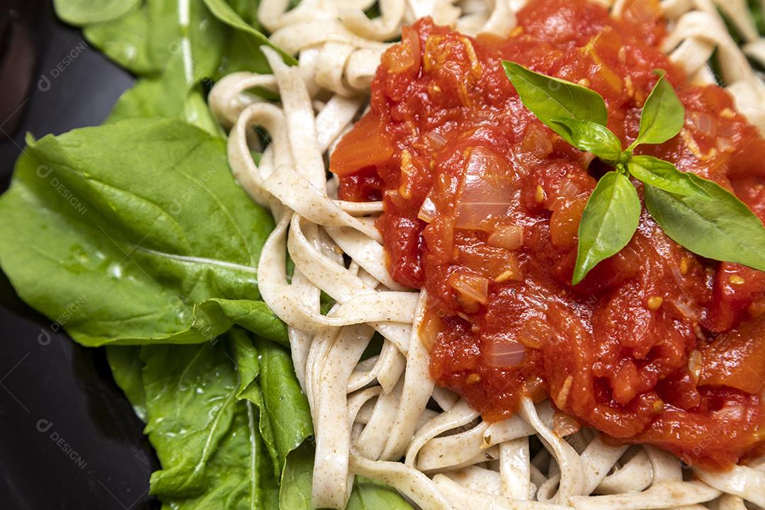 massa de massa integral com folhas verdes de rúcula, molho vermelho