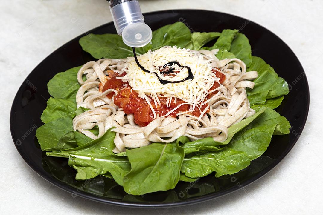 Colocando vinagre balsâmico em massa integral com queijo parmesão