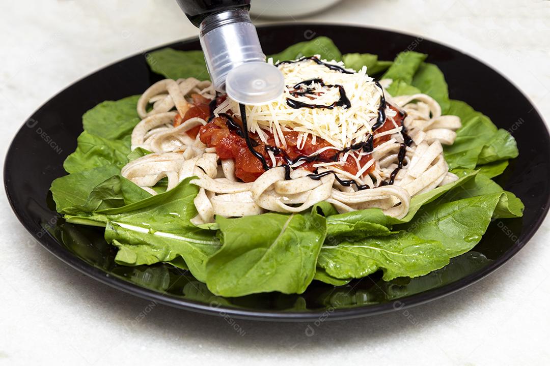 Colocando vinagre balsâmico em massa integral com queijo parmesão